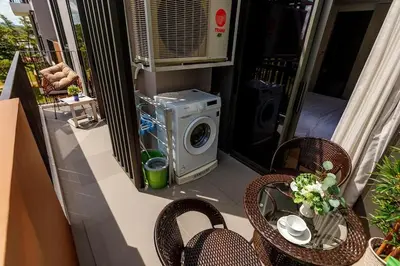 a balcony with a washing machine and chairs and a table at Sky Park Golg View 2BR Bang Tao Laguna in Laguna Phuket
