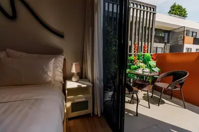 a bedroom with a bed and a balcony with a table at Sky Park Golg View 2BR Bang Tao Laguna in Laguna Phuket