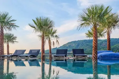 a swimming pool with palm trees and lounge chairs at Modern Residence Tropics CTG-L709 with Medical and Wellness Center in Kamala Beach
