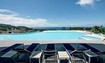 a large swimming pool with chairs and the ocean at The Seaview Kata in Kata Beach