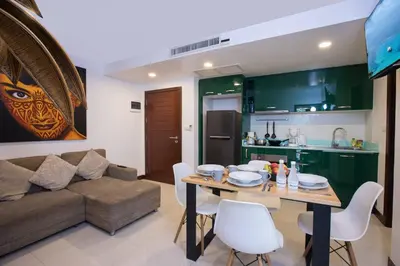 a kitchen and a living room with a table and a couch at Modern 2BR Condo at Karon Butterfly Phuket in Karon Beach