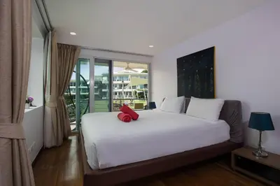 a bedroom with a white bed with a red object on it at Modern 2BR Condo at Karon Butterfly Phuket in Karon Beach