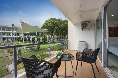a balcony with two chairs and a table with a view of a park at Modern 2BR Condo at Karon Butterfly Phuket in Karon Beach