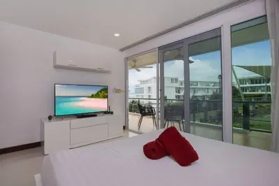 a bedroom with a bed with a television and a balcony at Modern 2BR Condo at Karon Butterfly Phuket in Karon Beach