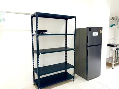a black book shelf next to a refrigerator at Patong Canal Villa 103 in Patong Beach