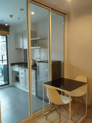 a kitchen with a black table and chairs and a refrigerator at The Base Height Phuket in Phuket Town