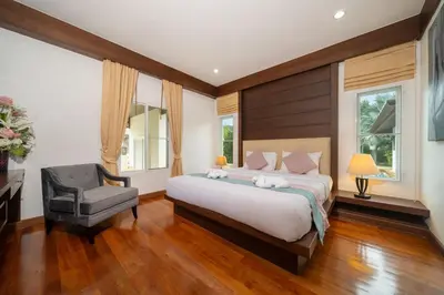 a bedroom with a large bed and a chair at Villa with Huge Private Pool and Tropical Garden Just 10 Minutes Walk to Kamala Beach in Kamala Beach