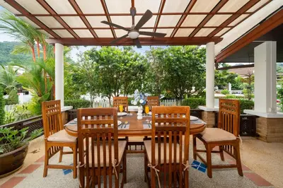 a wooden table and chairs on a patio at Villa with Huge Private Pool and Tropical Garden Just 10 Minutes Walk to Kamala Beach in Kamala Beach