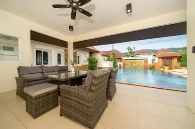 a patio with a table and chairs and a pool at Villa with Huge Private Pool and Tropical Garden Just 10 Minutes Walk to Kamala Beach in Kamala Beach