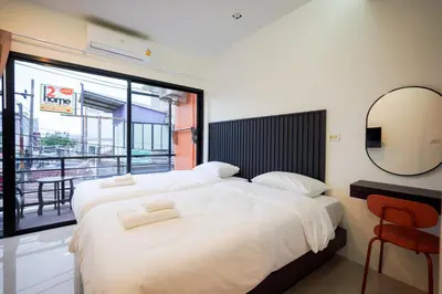 two beds in a room with a mirror and a window at Tiger Nest Stay in Ban Suan