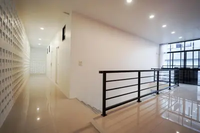 a hallway with white walls and a black railing at Tiger Nest Stay in Ban Suan