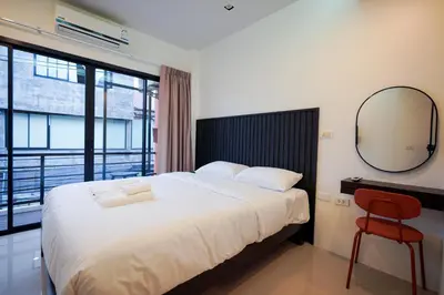 a bedroom with a bed and a mirror and a chair at Tiger Nest Stay in Ban Suan