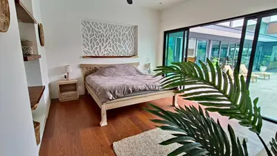 a bedroom with a bed and a plant at Sarang Jati Mansion in Ban Saiyuan (1)