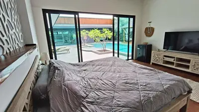a bedroom with a bed and a television and a pool at Sarang Jati Mansion in Ban Saiyuan (1)
