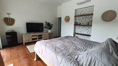 a bedroom with a bed and a flat screen tv at Sarang Jati Mansion in Ban Saiyuan (1)