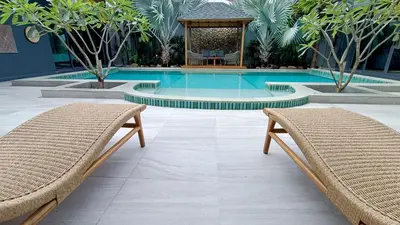 a swimming pool with two chairs and a gazebo at Sarang Jati Mansion in Ban Saiyuan (1)