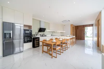 a large kitchen with a wooden table and chairs at Near Laguna 4 BR morden pool villa V9 in Ban Pak Lak