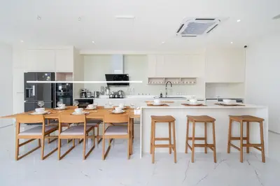 a white kitchen with a wooden table and chairs at Near Laguna 4 BR morden pool villa V9 in Ban Pak Lak