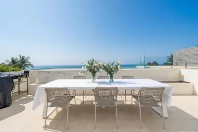 a white table and chairs on a balcony with the ocean at ANGSANA Coastal Bliss Penthouse 3bds Apartment with pool in Laguna Phuket