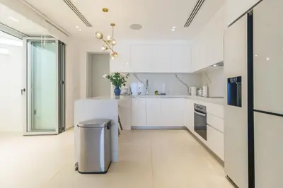 a kitchen with white cabinets and a stainless steel trash can at ANGSANA Coastal Bliss Penthouse 3bds Apartment with pool in Laguna Phuket