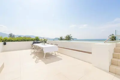 a white balcony with a table and a view of the ocean at ANGSANA Coastal Bliss Penthouse 3bds Apartment with pool in Laguna Phuket