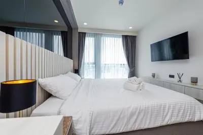 a bedroom with a large white bed and a television at Ozone Modern in Laguna Phuket