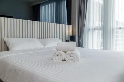a white bed with towels and a laptop on it at Ozone Modern in Laguna Phuket