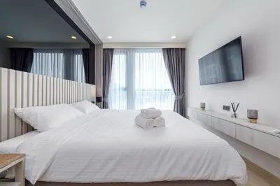 a bedroom with a large white bed with a towel on it at Ozone Modern in Laguna Phuket