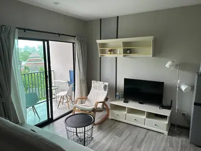 a living room with a flat screen tv and a balcony at Апартаменты Пхукет in Phuket Town
