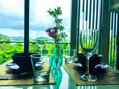 a table with glasses and a vase with flowers on it at Seaview At Cape Panwa in Panwa Beach