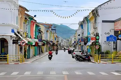 a man riding a motorcycle down a city street at XX Mitr Inn Phuket Island - Phuket Old Town in Phuket Town
