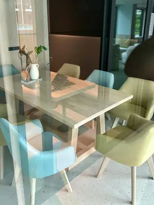 a wooden table with chairs and a glass table with a laptop at Flat near the beach with gym, pool, sauna and workspace in Ban Thalat Choeng Thale