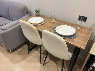 a wooden table with chairs and white plates on it at Flat near the beach with gym, pool, sauna and workspace in Ban Thalat Choeng Thale