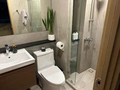 a bathroom with a toilet and a sink and a shower at Flat near the beach with gym, pool, sauna and workspace in Ban Thalat Choeng Thale