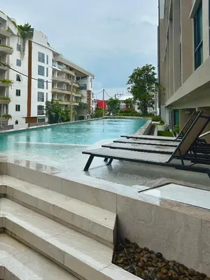 a swimming pool with a bench next to some buildings at Flat near the beach with gym, pool, sauna and workspace in Ban Thalat Choeng Thale