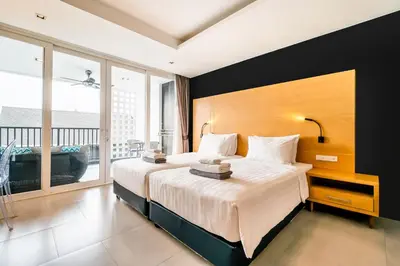 a bedroom with two beds and a large window at Vivace Hotel in Kamala Beach
