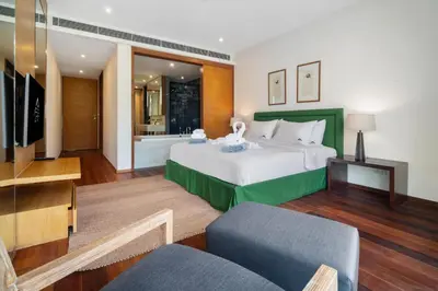 a bedroom with a large bed and a living room at Stylish 2BR Resort Condo with Seaview Surin in Phuket Town