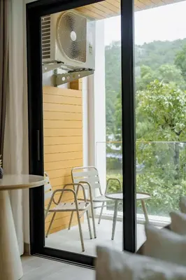 a room with a balcony with chairs and a table at Wyndham Gardens 2413 Elegant Studio Forest View in Phuket Town