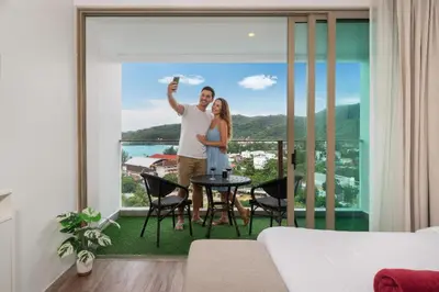 a man and woman standing on the balcony of a house at Studio Apt Seaview Balcony - Oceana C63 in Kamala Beach