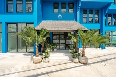 a blue building with palm trees in front of it at Blu Monkey Boutique Naiharn Beach in Nai Harn Beach