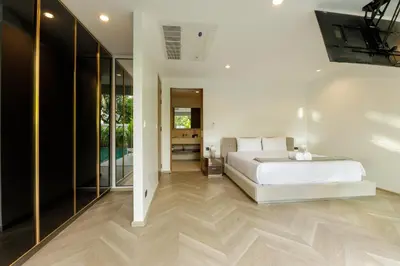 a bedroom with a large white bed and glass walls at Luxe & Privacy Orchard Villas Pasak 4BR in Laguna Phuket