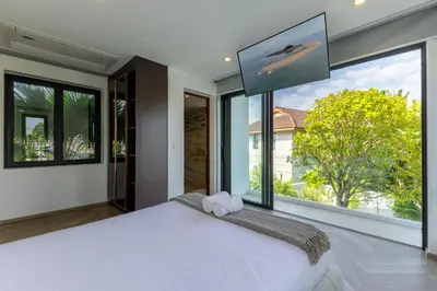 a bedroom with a large white bed and large windows at Luxe & Privacy Orchard Villas Pasak 4BR in Laguna Phuket