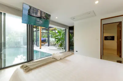 a bedroom with a large bed and a large window at Luxe & Privacy Orchard Villas Pasak 4BR in Laguna Phuket