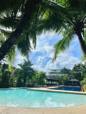 a swimming pool with palm trees in the foreground at Spacious 3 bedroom, 100m walk to Layan Beach in Phuket