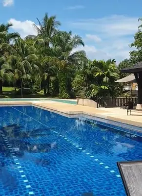 a blue swimming pool with palm trees in the background at Spacious 3 bedroom, 100m walk to Layan Beach in Phuket