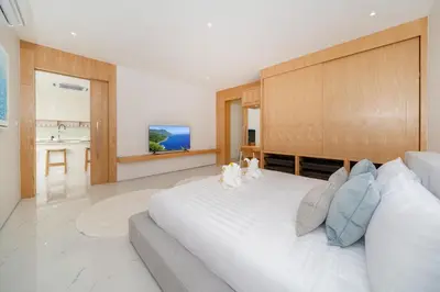 a large bedroom with a large white bed with blue pillows at Modern and elegant 4-bedroom pool villa suitable for families - V10 in Ban Pak Lak