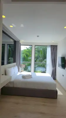 a bedroom with a large bed and a large window at The Ozon Condotel by SP in Laguna Phuket