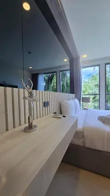 a bedroom with a large bed and a large window at The Ozon Condotel by SP in Laguna Phuket