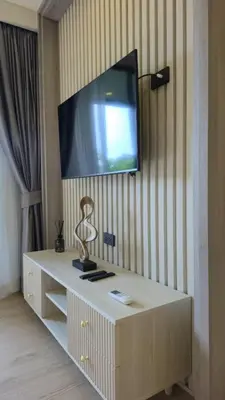 a flat screen tv on a wall with a cabinet at The Ozon Condotel by SP in Laguna Phuket