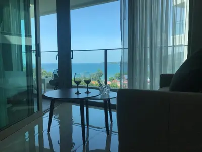 a table with two wine glasses on it in front of a window at OCEANA Kamala SeaviewCondo B41 in Kamala Beach